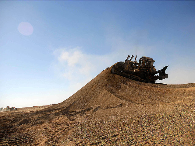Bulldozer pushing dirt uphill